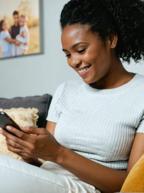A single parent gracefully balancing family responsibilities and dating life, checking their phone while engaging with their children in a comfortable home setting, symbolizing harmony between personal growth and family well-being.